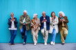 © CarlosBarquero - Group of elderly Caucasian laughing together using cell phone standing leaning on blue wall. Happy old friends with gray hair gathered having fun looking mobile outdoor. Mature people enjoying devices