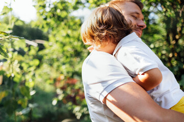 Happy dad holding his cute son in his arms in the garden