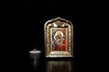 Fototapeta  - A lighted candle next to the icon of the Mother of God with the baby Jesus in her arms, on a black background. Decorative or ornamental image