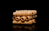 Fototapeta  - A bunch of cylinder shape waffles. Many coconut crispy roll wafers on a black background