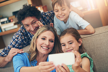 Wall Mural - Happy family, relax and selfie with peace sign for memory, picture or bonding together on sofa at home. Mom, dad and young children with smile for photography, capture or moment on living room couch