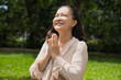 Healthy Happy smiling middle aged asian woman taking sunlight exposure in summer green park with good sun light and Ultraviolet, UV for vitamin D metabolism production