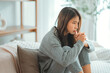 © oatawa - Depressed young woman sitting on couch in the living room at home, Frustrated confused female feels unhappy problem in personal life quarrel break up with boyfriend