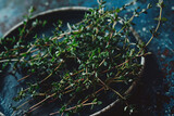 Fototapeta  - Fresh thyme herbs on a rustic plate with a dark moody background