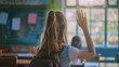 © Irina Sharnina - A smart schoolgirl sits at a desk in a classroom with his hand raised, wanting to give the correct answer or participate. Concept of education, primary school, learning
