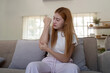 © Natee Meepian - Young woman examining her arm indoors, feeling discomfort