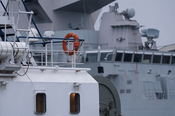 Wall Mural - TUBOAT AND WARSHIP - Auxiliary ship and Italian Navy guided missile frigate moored at the seaport wharf