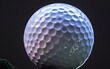 © OLGA - Close-up of a golf ball against a dark background.