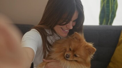 Sticker - A smiling woman in a cozy room takes a selfie with her adorable pomeranian dog