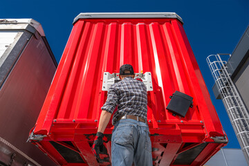 Wall Mural - Trucker performing maintenance on the rear of a red semi trailer