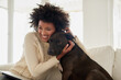 © peopleimages.com - Home, hug and black woman with dog, care and relax with happiness, bonding together and animal. Apartment, pet owner and girl with affection, peace and playful with embrace, best friend and loyalty