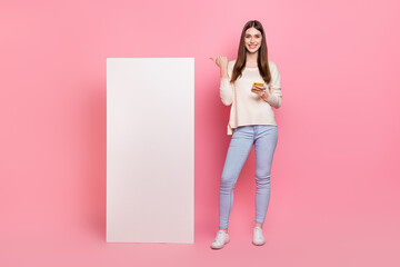 Canvas Print - Full length body size view of beautiful trendy girl using device showing copy space ad isolated over pink pastel color background