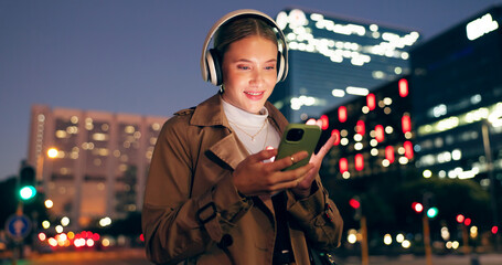 Canvas Print - Woman, outdoor and smile on smartphone with headphone for music playlist, entertainment at night in New York. Female person, happy and internet for streaming platform with song or album and video