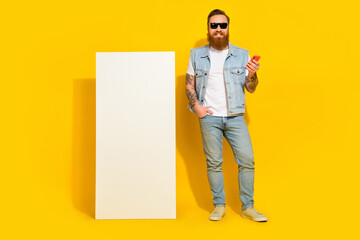 Wall Mural - Photo of attractive funky man wear jeans waistcoat sunglass typing modern device empty space isolated yellow color background