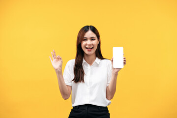 Young asian woman wearing white short sleeve shirt and smiling while holding smartphone with blank screen