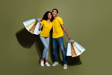 Wall Mural - Full body portrait of two nice people hold shop bags empty space wear t-shirt isolated on khaki color background