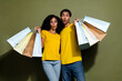 Portrait of two nice people hold mall bags wear t-shirt isolated on khaki color background