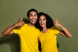 Portrait of two nice people demonstrate thumb up wear t-shirt isolated on khaki color background
