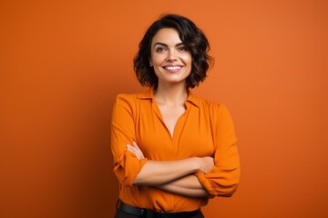 Poster - Portrait of a happy woman in her 30s with arms crossed in soft orange background