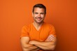 © Markus Schröder - Portrait of a joyful man in his 30s with arms crossed isolated in soft orange background