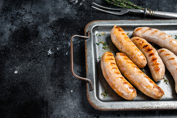 Wall Mural - Grilled Bratwurst and Chorizo sausages on a steel serving tray. Black background. Top view. Copy space