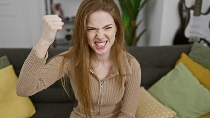 Poster - Furious young blonde woman, wearing sweater, expresses extreme anger at home; frustrated and aggressive, clenches fist in furious rage