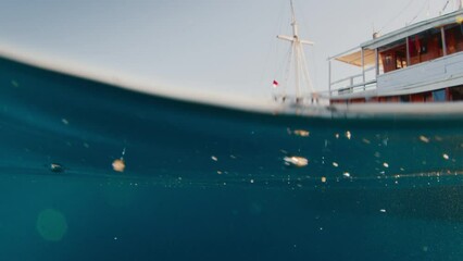 Wall Mural - Splitted footage above and underwater of the boat in the tropical sea