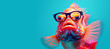 Creative image of tropical fish with umbrella and spectacles on blue background