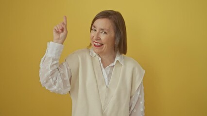 Wall Mural - Successful middle age hispanic woman, standing over yellow background, pointing finger up in excitement of a great idea, signifying number one success