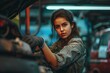 © anatolir - Young woman in a garage fixing a car, looking determined and focused