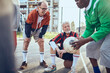 © Davor - Senior soccer team taking a break and strategizing during game on urban court