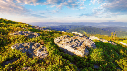 Wall Mural - stone on the grassy hillside at sunrise. view in to the distant valley of carpathian mountains. pere