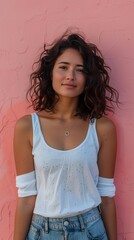 Wall Mural - A young woman clad in a white tank top and denim shorts stands against a vibrant pink wall