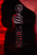 © Granmedia - Close-up of female hands in black gloves holding a BDSM whip on a red background. BDSM is an outfit for adult sex games. Sex shop Adult store