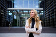 © CarlosBarquero - Modern stylish Caucasian adult business woman dressed in formal suit standing in work place outdoor. Strong and empowered female happy with shaved head looking smiling to the side. Copy space