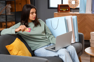 Poster - Young woman with credit card and laptop shopping online at home