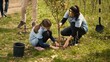 © DC Studio - Group of volunteers planting new seedlings around the forest area, digging up holes and installing trees seeds for nature conservation and protection. Mother and little girl take action. Camera A.