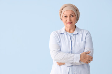 Wall Mural - Smiling mature woman after chemotherapy on blue background. Stomach cancer concept