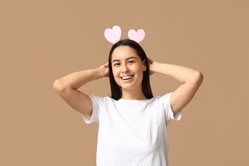 Canvas Print - Funny young woman with paper hearts on beige background