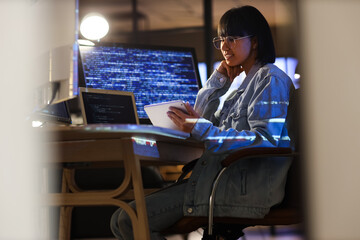 female programmer working with tablet computer in office at night
