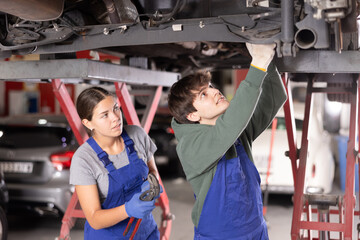 Wall Mural - Experienced auto mechanic tells a novice auto mechanic how to properly repair a car at a car service center.