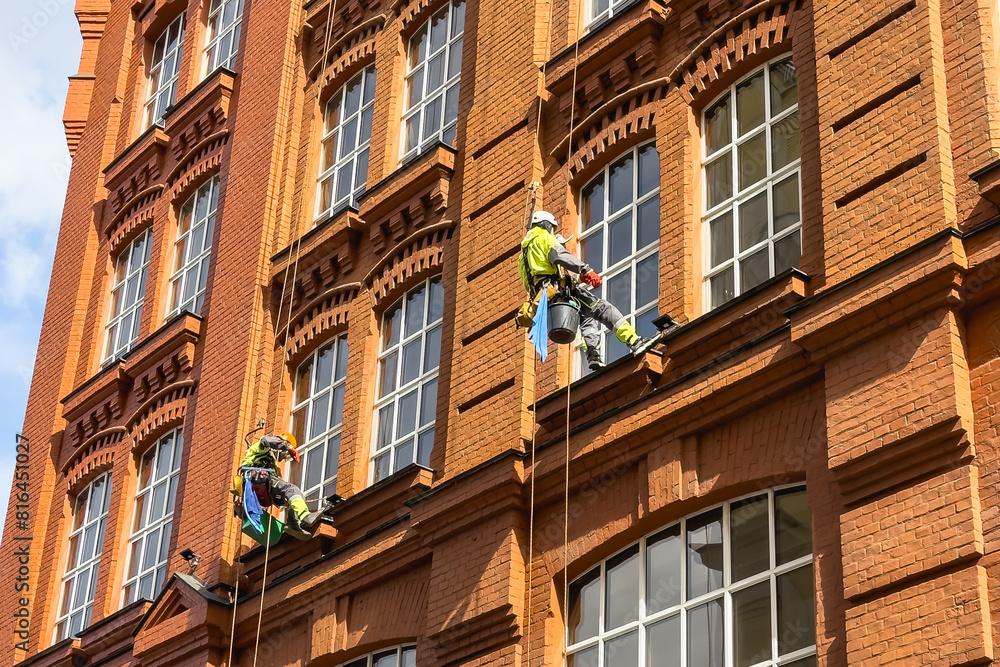 Window Cleaner In Building Window cleaners wash windows at height on the facade of a brick ...