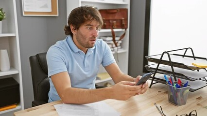 Poster - Shock and surprise, young caucasian man afraid, covering mouth with hand at office, using smartphone