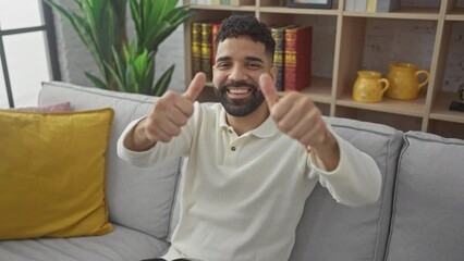 Wall Mural - Thumbs up! a young, hispanic man at home, radiating positivity with happy successful gesture, smiling from the joy of success, approving with a hand sign