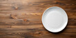 Top view of blank white food plate on a wood background