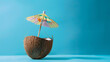 © Mangata Imagine - A mini coconut cocktail with an umbrella on a blue background, minimal concept photography. Summer vacation concept