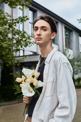 Wall Mural - A young, stylishly dressed man proudly holds a bouquet of colorful flowers in front of a grand building.