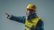 © Mikus - A man in a yellow safety vest and hard hat, points toward his side