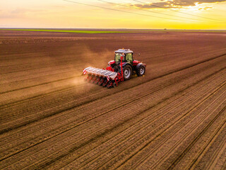 Wall Mural - Aerial shot of a farmer seeding, sowing crops at field. Sowing is the process of planting seeds in the ground as part of the early spring time agricultural activities.