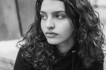 White brunette teenage girl with curly hair poses on the street in the city.